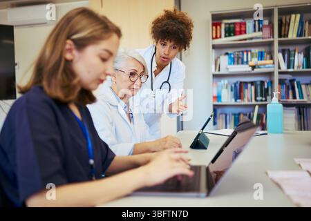 Medical team collaborating on patient care using laptop and digital tablet Stock Photo