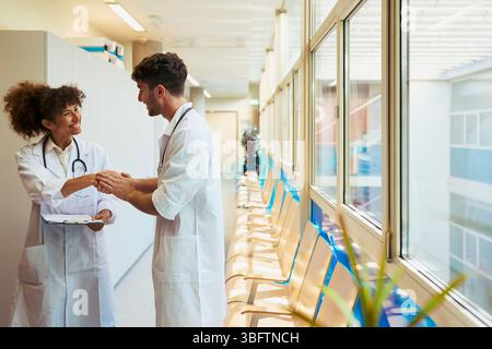 Doctors shaking hands in hospital corridor: healthcare teamwork and collaboration Stock Photo