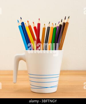 Colorful crayons in the pot placed on the wood desk Stock Photo