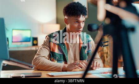 Man, streamer and computer in home with typing, mic or review with script editing for video production. Gen z influencer, reading and pc for feedback Stock Photo