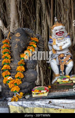 Bali, Indonesia - Dec 10, 2024: Statues of a monkey and elephants. The table is covered with fruit and a yellow cloth Stock Photo