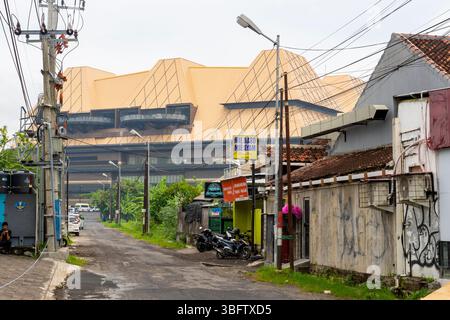 Bali, Indonesia - Dec 10, 2024: Street with a building in the background. There are motorcycles parked on the side of the road Stock Photo