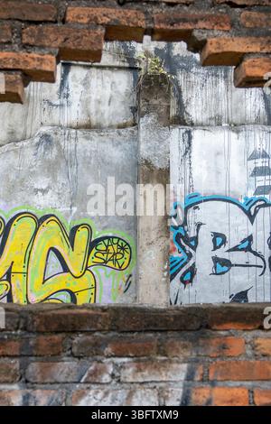 Bali, Indonesia - Dec 10, 2024: Wall with graffiti on it and a hole in it. The graffiti is mostly yellow and blue Stock Photo