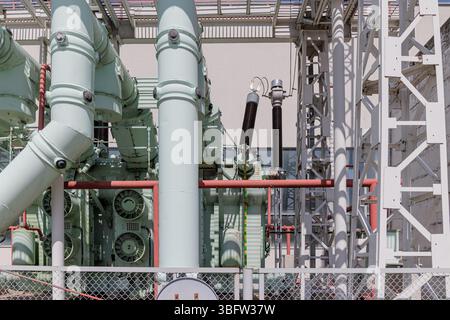 Electrical power substation with large transformer, insulators, and high-voltage components behind safety fencing. High quality photo Stock Photo