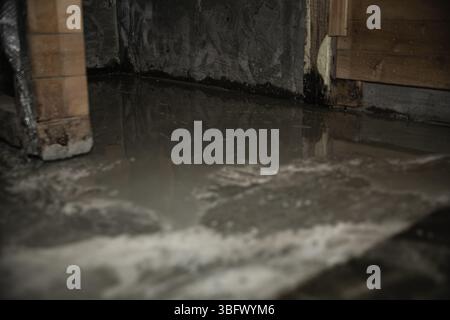 Wet concrete floor inside wooden structure during construction or renovation  Wet concrete floor inside wooden structure during construction or renova Stock Photo