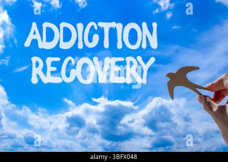 Addiction recovery symbol. Concept words Addiction recovery on beautiful blue sky. Psychologist hand, wooden bird. Beautiful blue sky cloud background Stock Photo