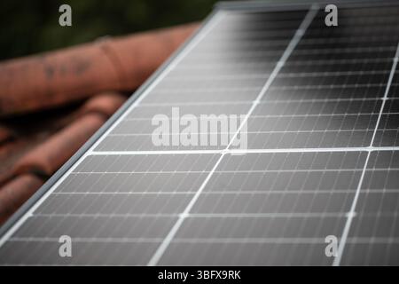 Angled view of solar panels on rooftop with old red tiles in soft diffuse light, concept for renewable energy and sustainable technology Stock Photo