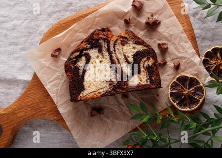 slice of marble cake with chocolate swirl on parchment paper, rustic dessert, wooden background Stock Photo