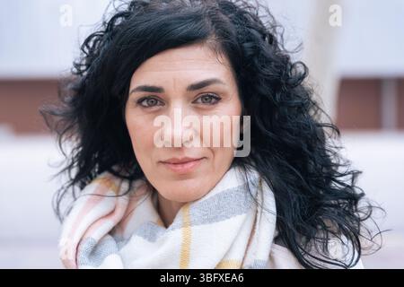 individual portrait Confident woman with curly black hair and scarf smiling  Stock Photo