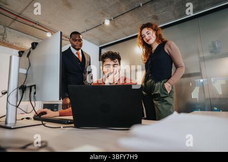 Three business professionals discussing plans together in a modern rustic office environment Stock Photo