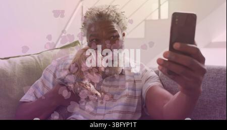 Image of falling hearts over african american senior man using smartphone Stock Photo