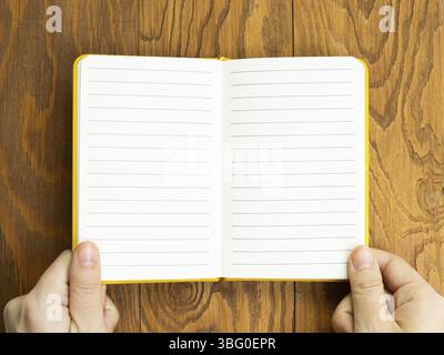 Hands open empty notebook on wooden desk. top view, copy space Stock Photo