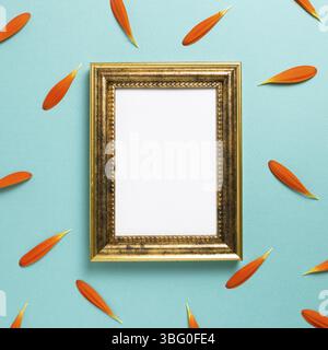 Empty photo frame with orange gerbera daisy flower petals on blue background. Floral composition, flat lay, top view, copy space Stock Photo