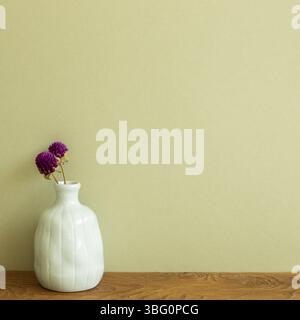 Vase of purple globe amaranth flowers on wooden table. khaki green background. copy space Stock Photo