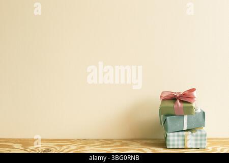 Stack of green gift boxes on wooden table. beige wall background Stock Photo