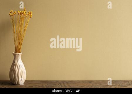 Vase of yellow dry flowers on wooden table with brown background. copy space Stock Photo