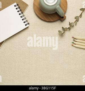 Work and study place. Notebooks, mug cup, colored pencils on beige fabric background. flat lay, top view, copy space Stock Photo