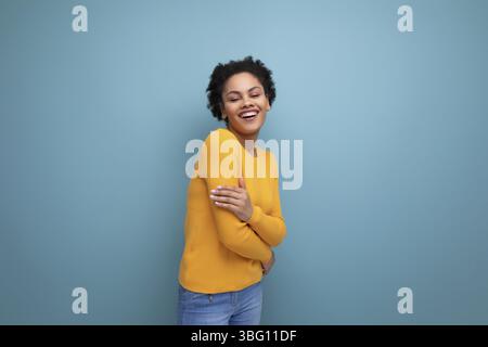 Cute well-groomed young brunette latin female adult in a yellow sweater on a studio background with copy space Stock Photo