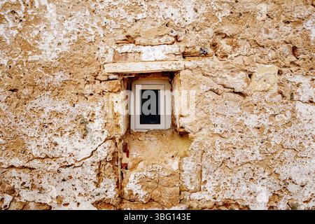 Small Window in an Ancient Rough Stone Wall. Rustic Building Detail, Textured Surface, Historical Architecture, Old Facade, Weathered Material Stock Photo