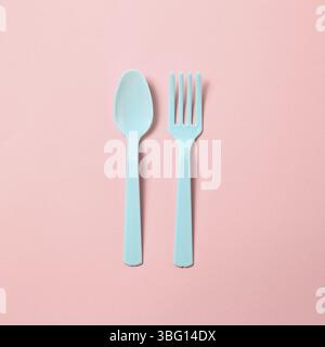 Blue plastic fork and spoon isolated on pink background Stock Photo
