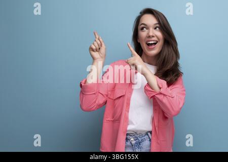 Stylish brunette woman in trendy shirt rejoices on studio background Stock Photo