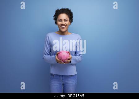 Pretty young latina brunette woman keeps savings in a piggy bank Stock Photo