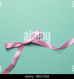 Decorative pink bow ribbon on mint background Stock Photo
