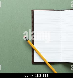 Open notebook and pencil on green background. top view, copy space Stock Photo