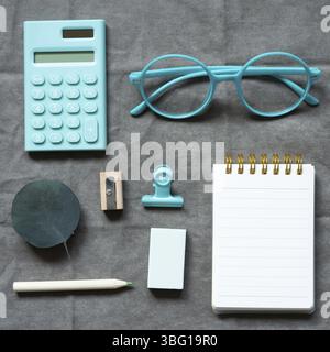 Mint calculator, eyeglasses, notebook and office supply on gray fabric background. flat lay, top view Stock Photo