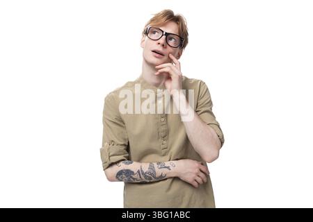 Young inspired european male student with red golden hair dressed in light brown shirt dreaming looking up Stock Photo