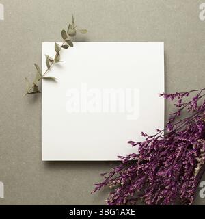 Empty memo paper with pink misty blue dry flowers and eucalyptus leaves on gray background. top view, copy space Stock Photo