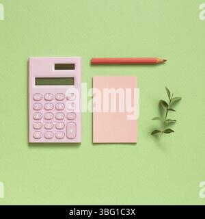 Pink digital calculator and memo note pad and colored pencil on pastel green background Stock Photo