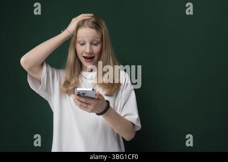 A woman is seen holding a cell phone in her hand and looking at the screen with a focused expression. She appears engaged in the content displayed on Stock Photo