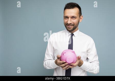Photo of positive self-confident young handsome brunet unshaven male businessman with beard wearing casual white shirt and tie isolated over blue back Stock Photo