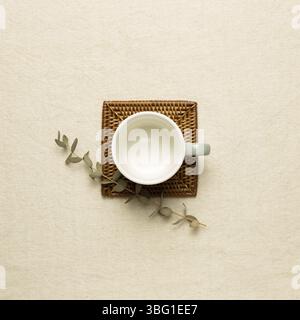 Empty mug cup with eucalyptus leaf on beige fabric background. top view Stock Photo