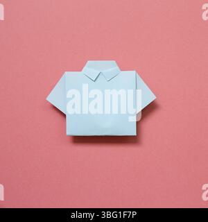 Blue paper shirt origami on pink background Stock Photo