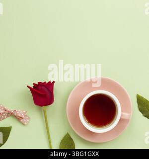 Cup of black tea with red rose on green background. Flat lay, top view, copy space Stock Photo