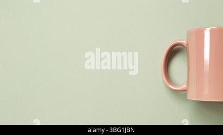 Pink mug cup on green background. copy space Stock Photo