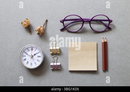 Memo pad, pencil, clock, clip, glasses on gray background. workspace. flat lay, top view, copy space Stock Photo