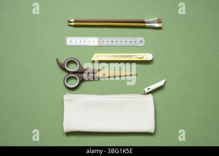 School office writing supplies and pencil case on green desk. top view, copy space Stock Photo