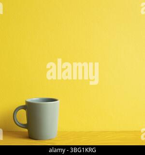 Gray mug cup on wooden table. yellow background Stock Photo