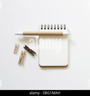 Empty notebook with pen, wooden clip on white background. top view, copy space Stock Photo