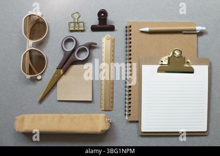 Brown notebook, clipboard, pen, ruler, clip, memopad, pencil case, scissors, eyeglasses on gray desk background. workspace office supply . flat lay, t Stock Photo