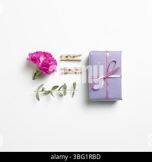 Purple gift box with carnation flower on white background. flat lay, top view, copy space Stock Photo