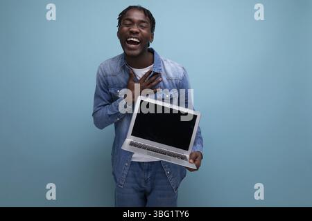 Successful freelancer american man with dreadlocks in denim jacket works remotely using laptop Stock Photo