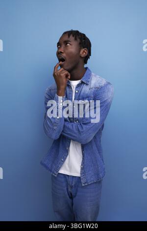 Close-up portrait of a surprised young african guy with dreadlocks in a denim jacket Stock Photo