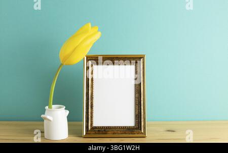 Photo frame with yellow tulip flower on wooden table with green background. floral arrangement, copy space Stock Photo