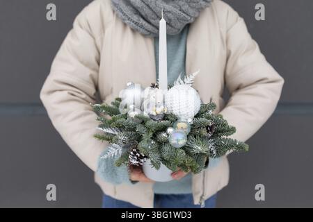 A person is holding a festive Christmas arrangement in their hands, showcasing traditional holiday decorations and colors Stock Photo
