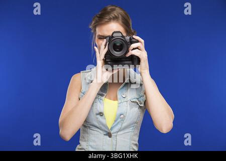 Girl with a camera in hand on blue background Stock Photo