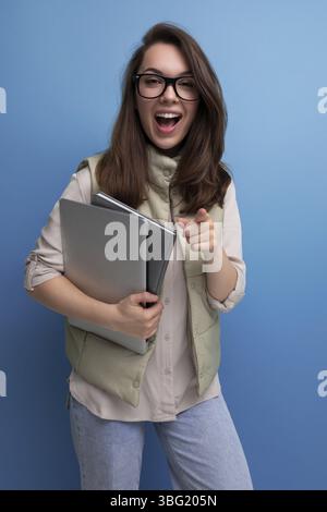 Positive 30s lady student holding documents and laptop on empty space background Stock Photo